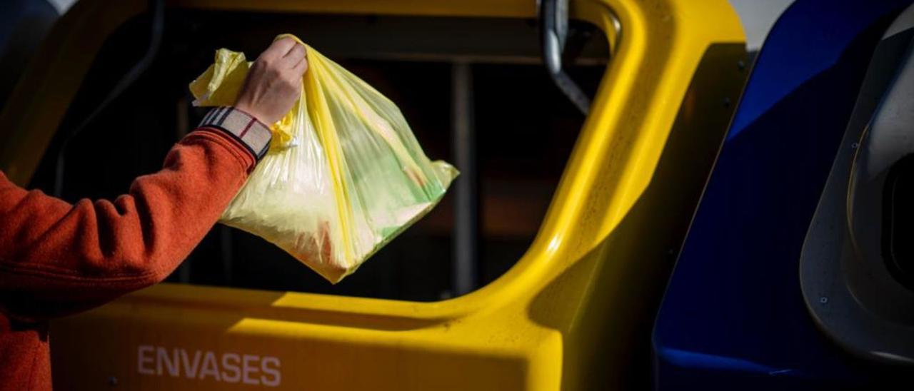 Una persona deposita una bolsa con plásticos en el contenedor amarillo destinado al reciclaje de envases.