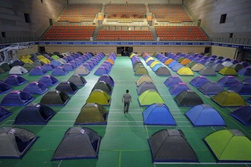 Man walks amidst tents set up on the floor of a gymnasium for parents of freshmen students at Tianjin University in Tianjin municipality