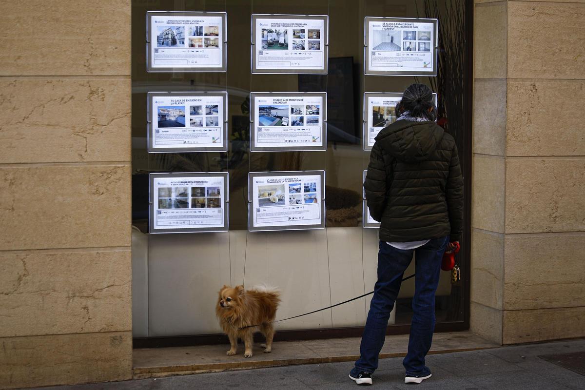 Una mujer observa los inmuebles en venta en el escaparate de una inmobiliaria