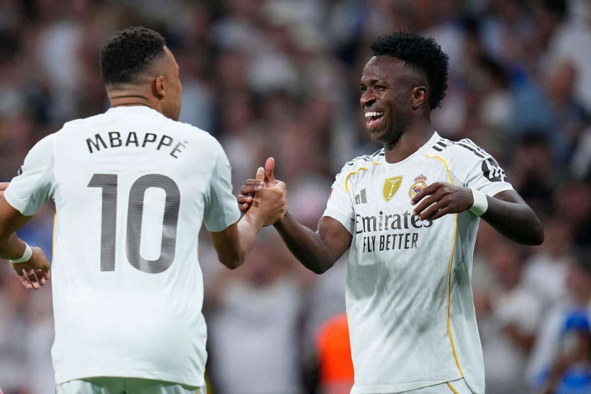 Real Madrid's Vinicius Junior, centre, celebrates with Kylian Mbappe, left, and Dani Ceballos after scoring the opening goal during the Spanish La Liga soccer match between Real Madrid and Villarreal at the Santiago Bernabeu stadium in Madrid, Spain, Saturday, Oct. 4, 2025. (AP Photo/Manu Fernandez)
