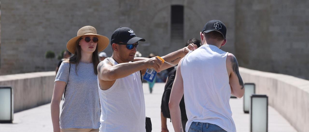 Unos turistas se aplican crema protectora contra el calor en el Puente Romano de Córdoba.