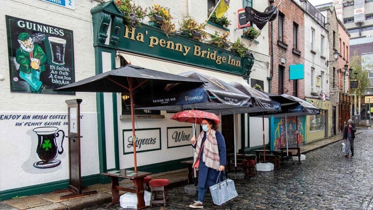 Una mujer con mascarilla pasa por una céntrica calle de Dublín.