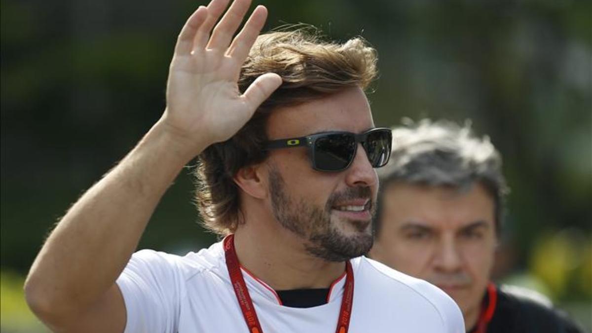 Fernando Alonso saluda a los aficionados a su llegada al circuito de Marina Bay