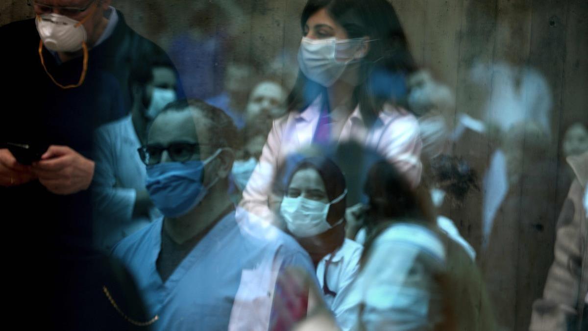 Medical staff members of the Saint George Hospital University Medical Centre  in charge of COVID-19 coronavirus patients  are seen in reflections off a window as they listen to music played by a band thanking them for their efforts to support patients during the novel coronavirus pandemic  in Lebanon s capital Beirut on April 24  2020  (Photo by PATRICK BAZ   AFP)