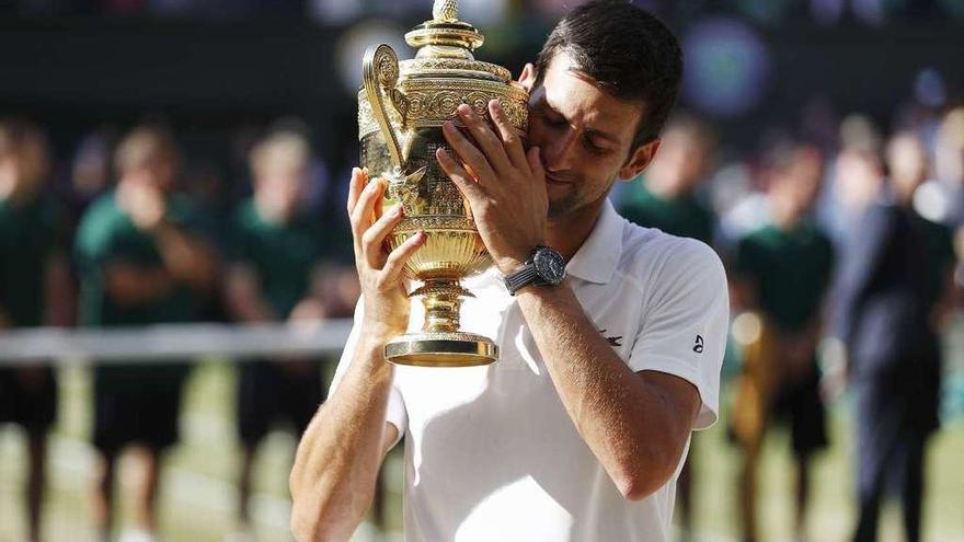 Djokovic se abraza al trofeo que le acredita como campeón de Wimbledon. // Efe