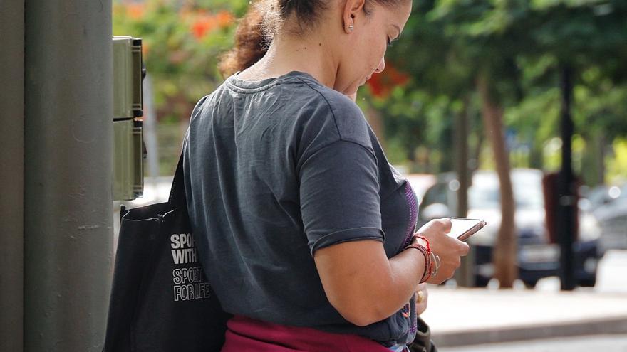 Una joven revisa su móvil mientras pasea por una calle de Santa Cruz.