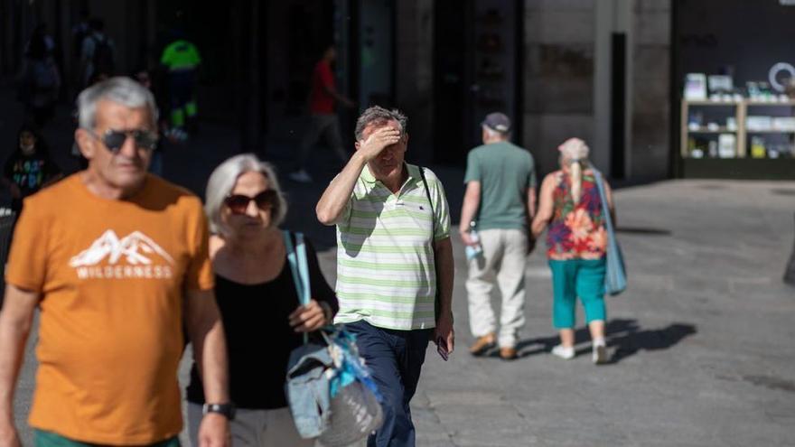 Un turista se cubre del sol con la mano mientras pasea por el centro de Zamora.