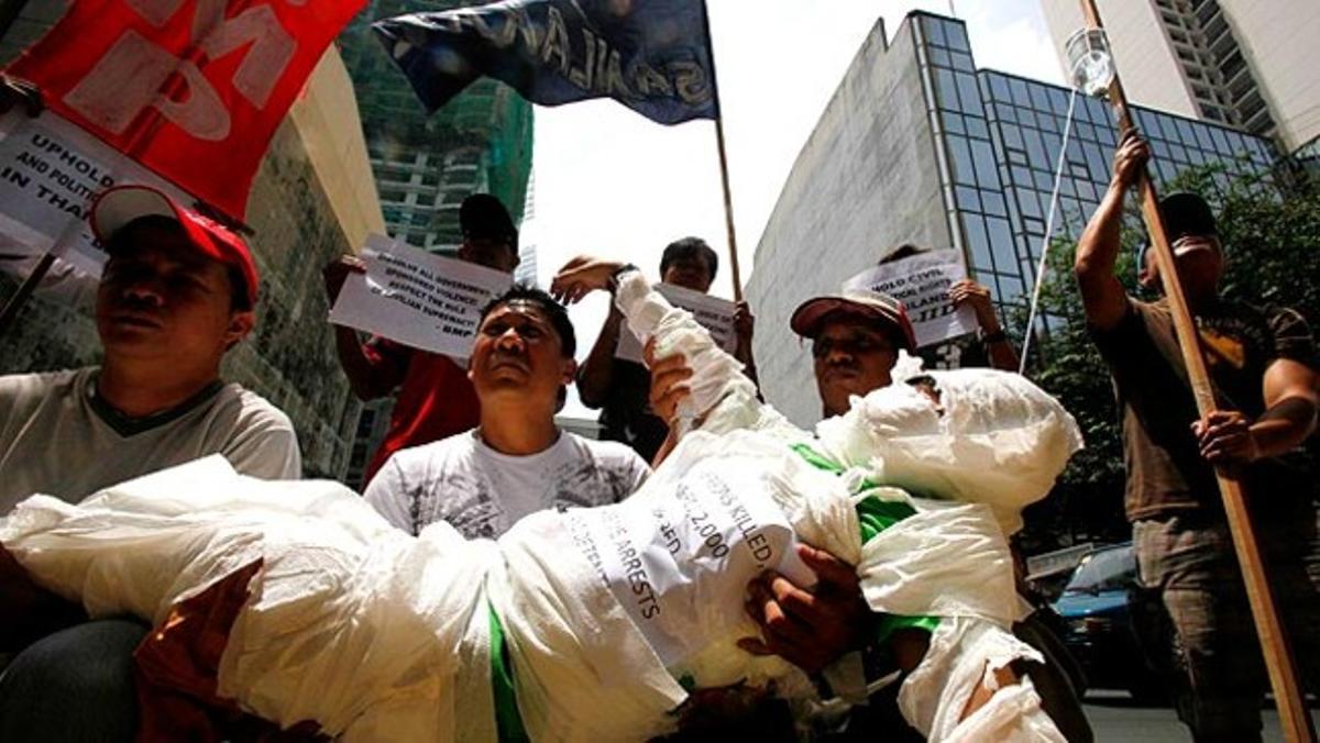 Vestit com una víctima de la violència política que afecta Tailàndia, un manifestant és portat pels seus companys cap a l’ambaixada tailandesa a Manila (Filipines).