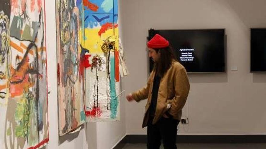 El artista ovetense Manuel García, mirando sus obras expuestas en Gijón por la Muestra de Artes Plásticas de Asturias.