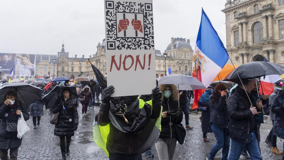 Un manifestante en Paris con una pancarta sobre las restricciones del coronavirus.