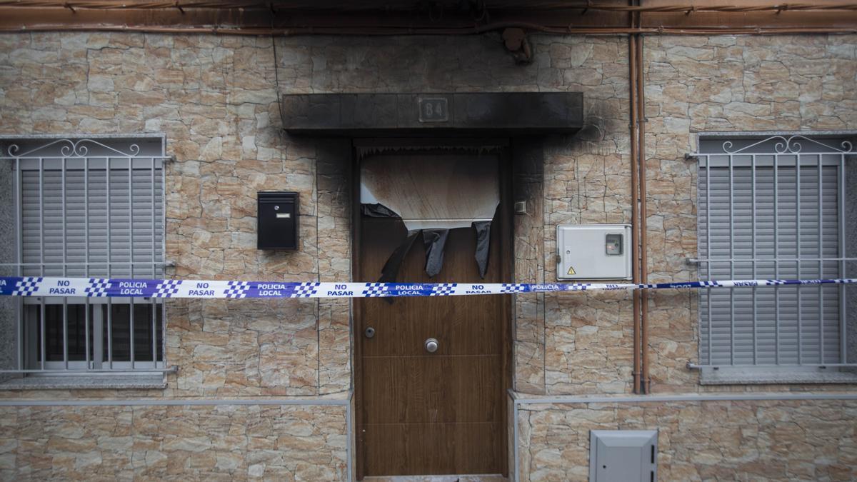 Daños en la puerta de la vivienda donde se ha producido el incendio mortal en Paterna.