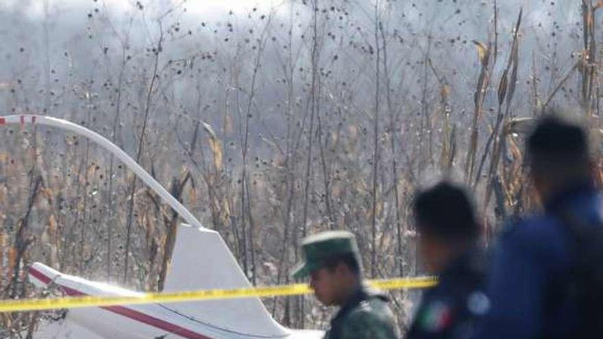 Peritos de la Fiscalía de Puebla, con los restos del helicóptero al fondo.