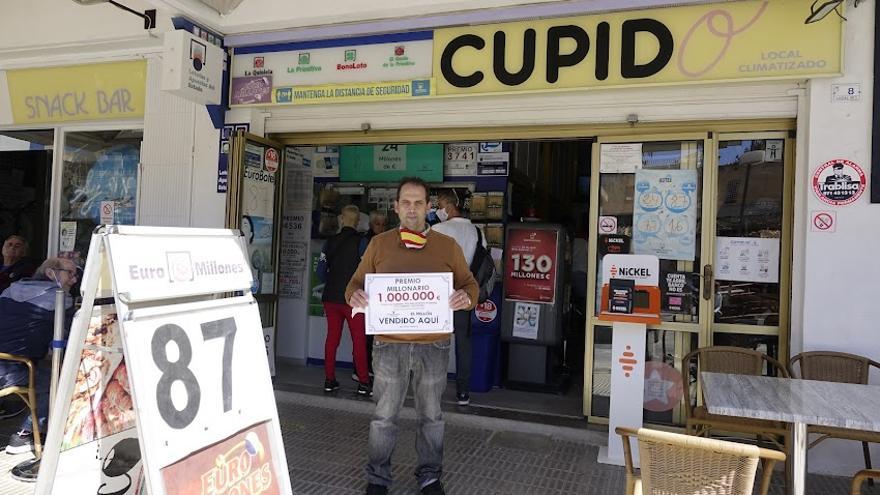 Francisco Javier Cañueto, responsable del bar Cupido de Magaluf, con el cartel que anuncia el premio entregado.