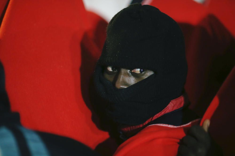 A migrant looks on under the rain after ...