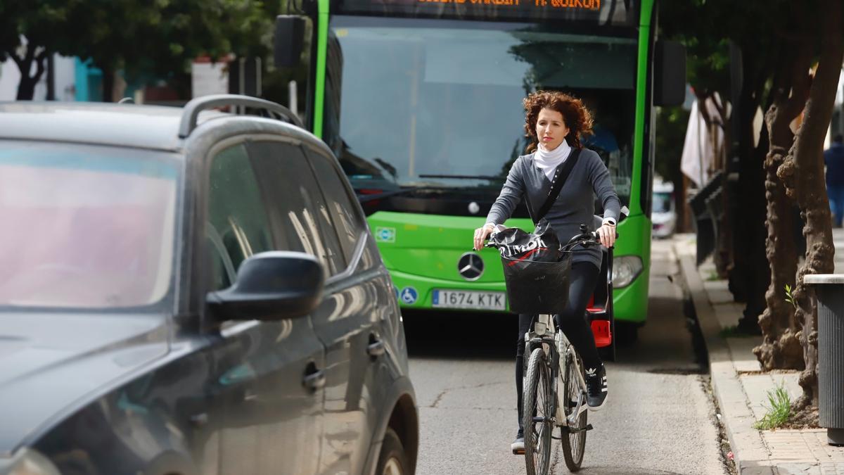 Una ciclista circula entre un autobús de Aucorsa y un vehículo.