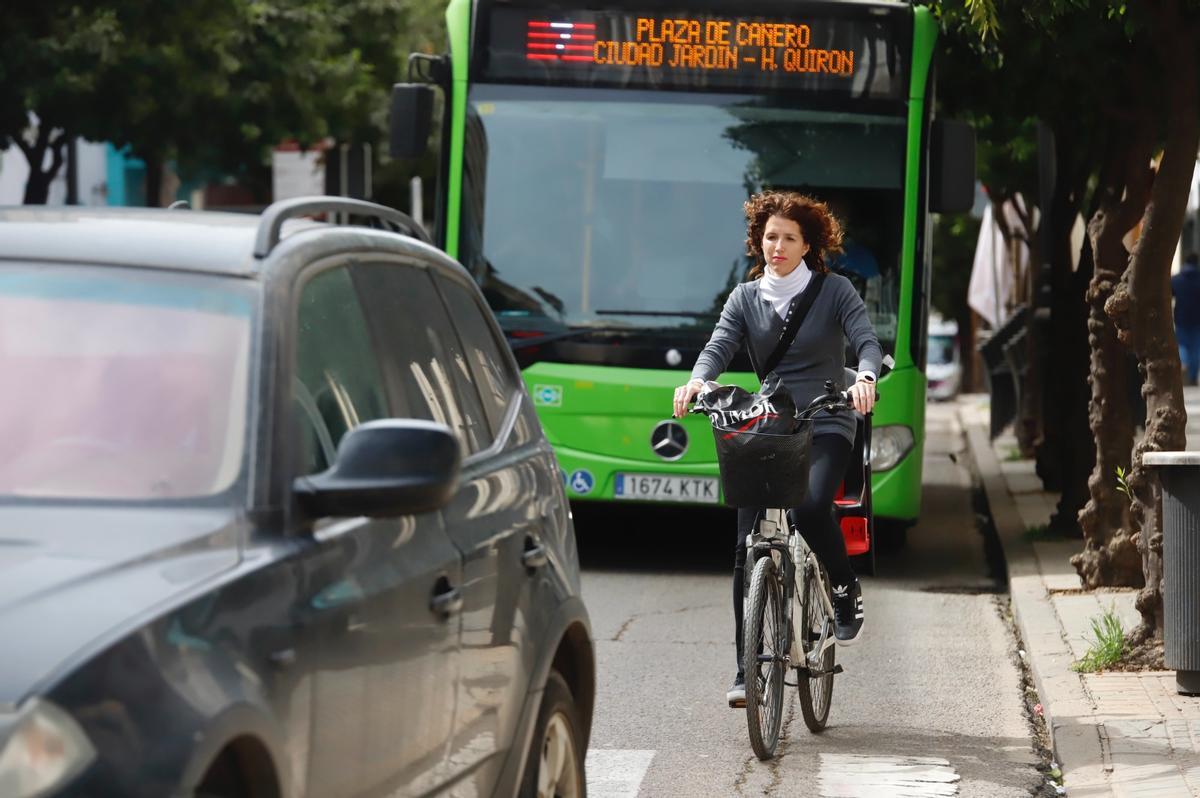 Una ciclista circula entre un autobús de Aucorsa y un vehículo.