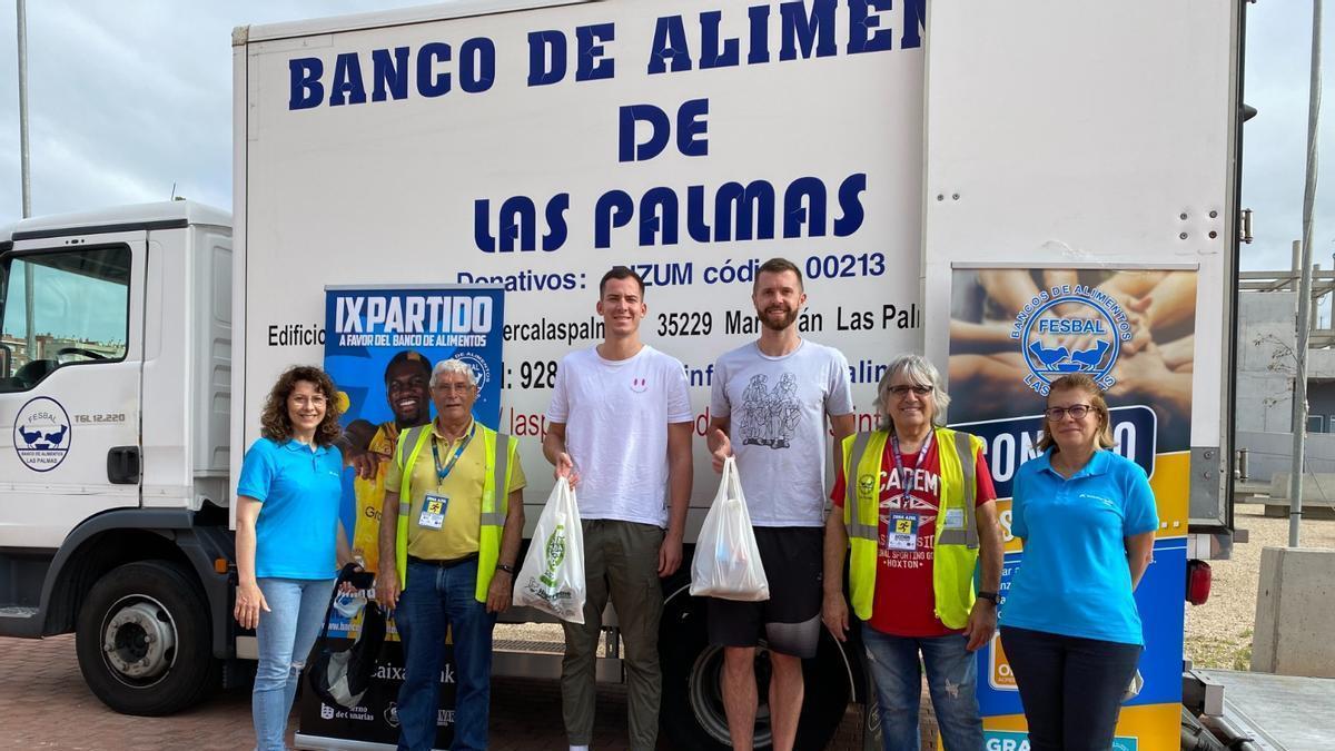 Miquel Salvó y John Shurna, en el centro de la imagen, durante el acto de entrega de los 10.000 kilos de alimentos a una representación del Banco de Alimentos