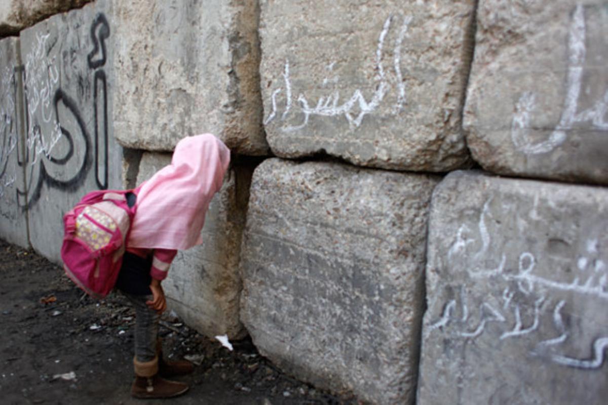 Un nena observa les tropes de l’exèrcit a través d’una escletxa de la barrera que han construït els militars per bloquejar les carreteres al Caire (Egipte).