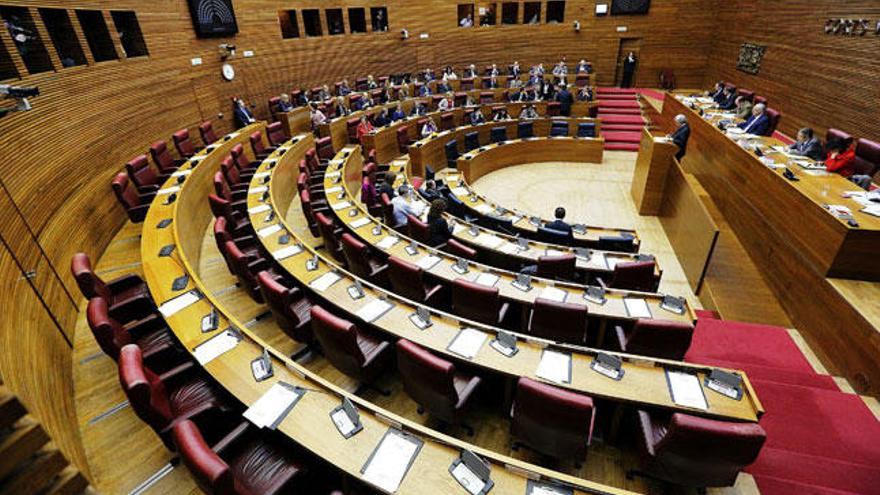 Vista del hemiciclo de Les Corts Valencianes donde en primer plano se observan prácticamente vacíos los escaños de los diputados de la oposición que han secundado la huelga general, mientras que al fondo ocupan sus asientos los parlamentarios del PP.
