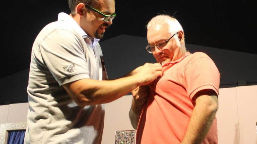 El presidente de la asociación cultural &quot;El Hórreo&quot; de Barcia, Pedro García, impone la insignia de oro del colectivo a Adolfo Camilo Díaz.