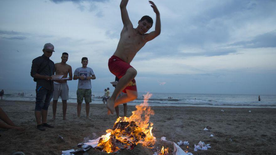 Imagen de archivo de un joven saltando una hoguera en la playa