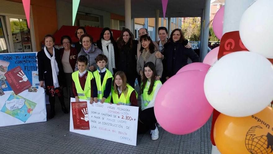 Alumnos, docentes y responsables de Manos Unidas, con el cheque logrado.