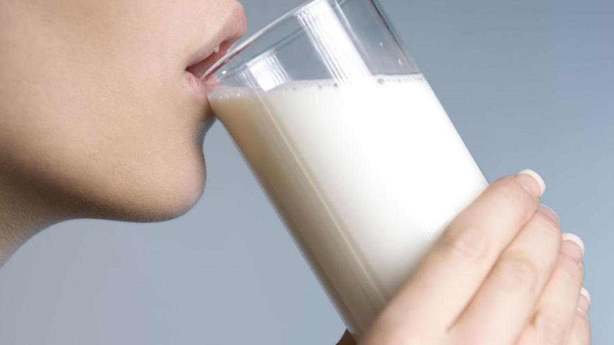 Una mujer bebe un vaso de leche.
