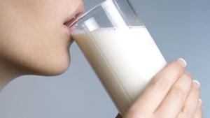 Una mujer bebe un vaso de leche.