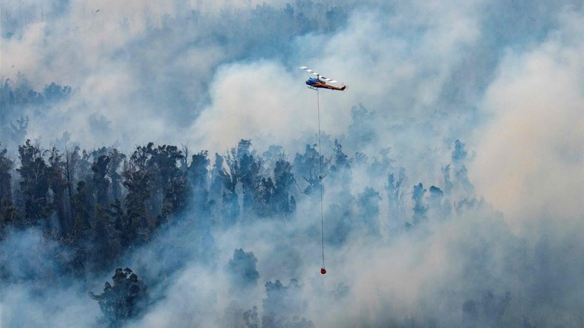 Un helicóptero lanza agua sobre un fuego en el departamento de Victoria.