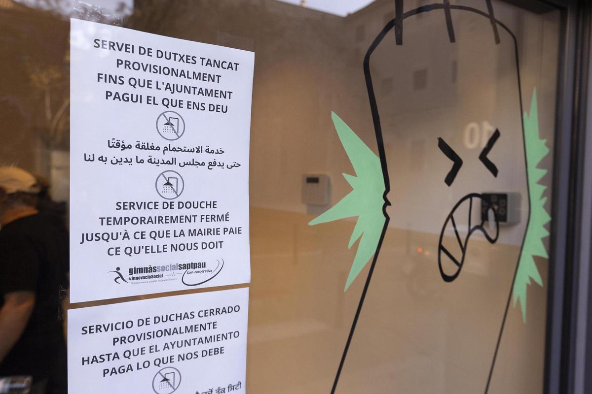 Un cartel avisa del cierre de las duchas solidarias en el Gimnasio Social Sant Pau, en Barcelona.