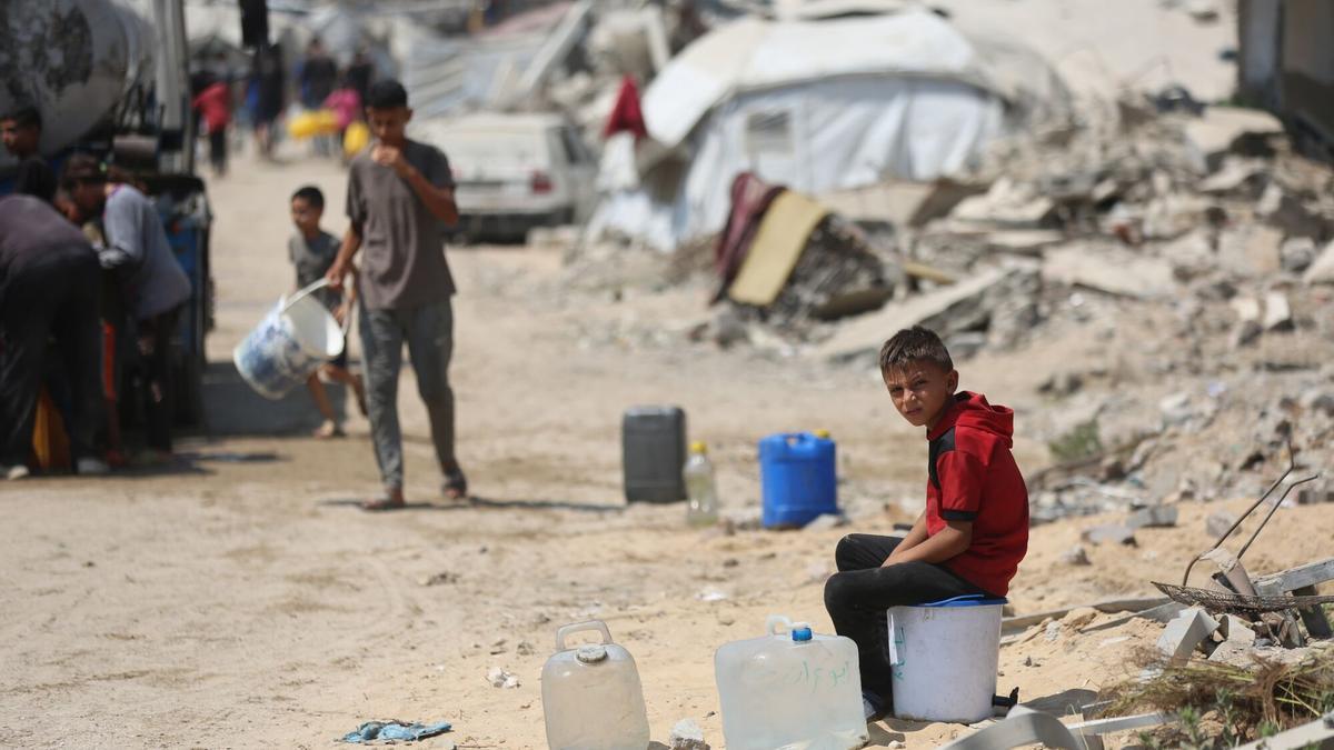 Niños palestinos esperan para intentar recoger agua en la Franja de Gaza.