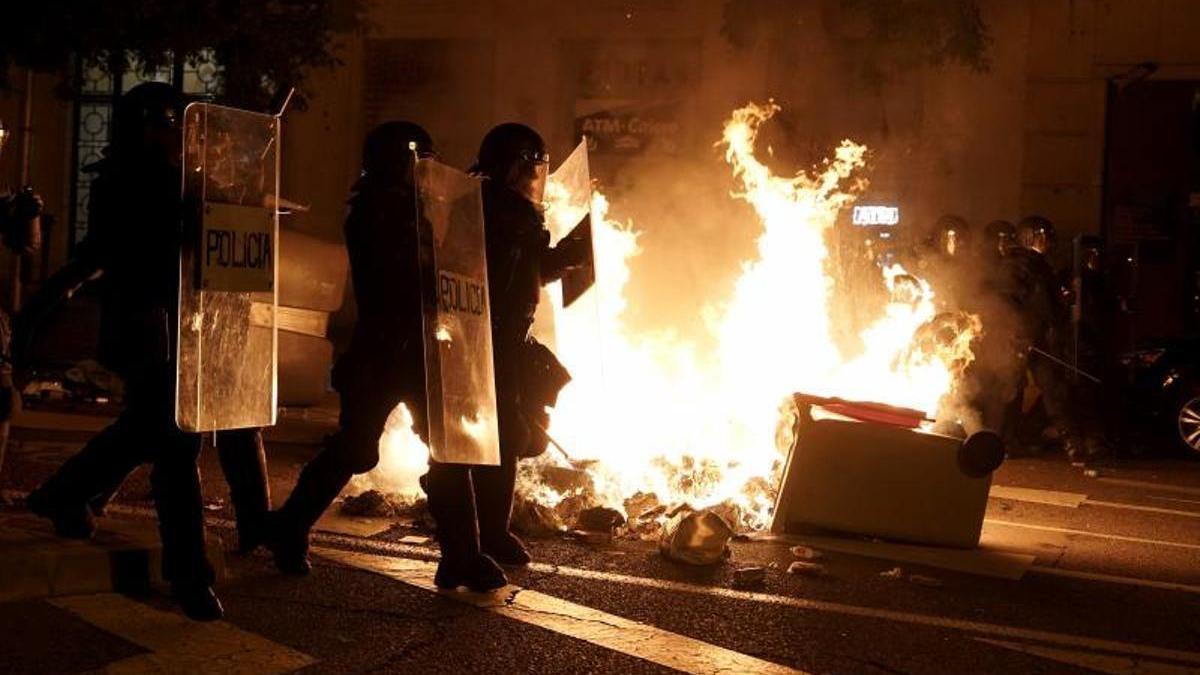 Un contenedor arde junto a unos antidisturbios en los desórdenes de la calle Ferraz de Madrid el 7 de noviembre.