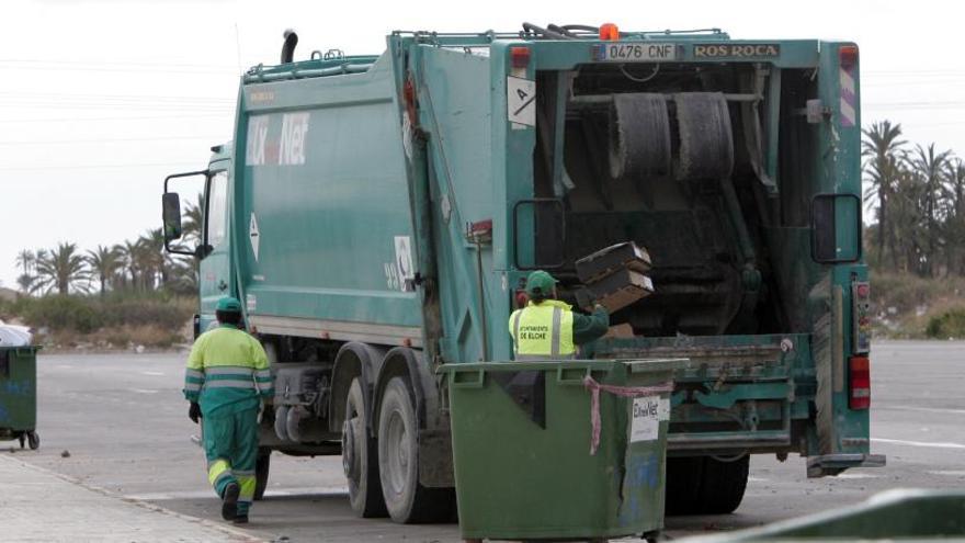 Dos operarios vacían contenedores de basura en un camión.