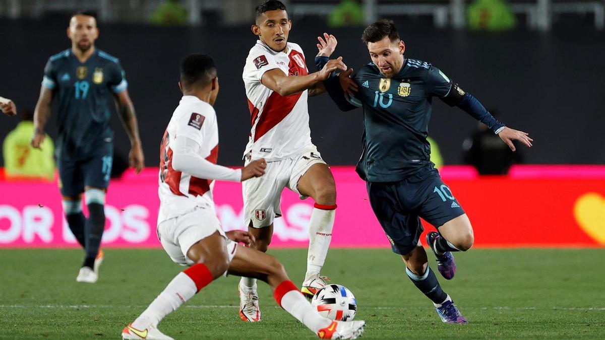 Leo Messi conduce el balón entre dos futbolistas peruanos en el Argentina - Perú.