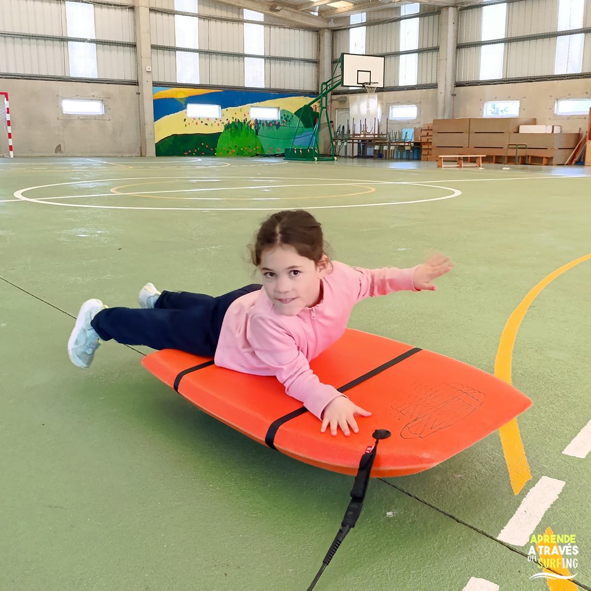 Unha alumna do CEIP Nétoma-Razo sobre unha táboa de surf.