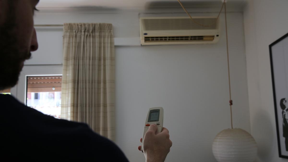 Un hombre enciende un aparato de aire acondicionado.