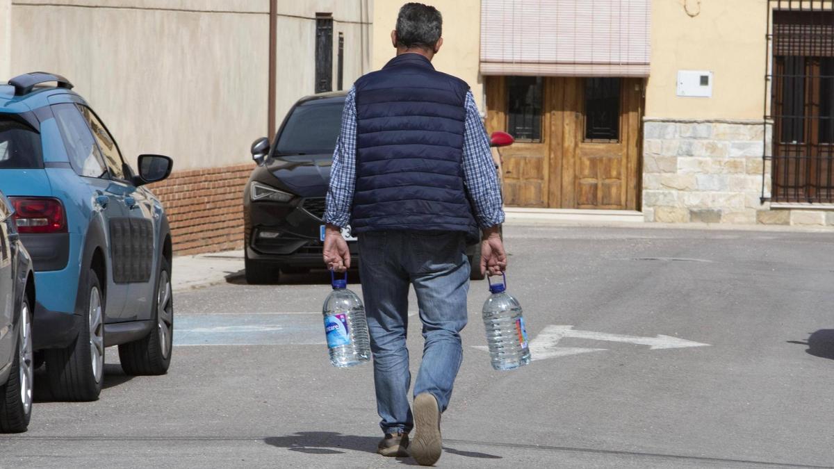 Un hombre carga garrafas de agua en un municipio afectado por nitratos.