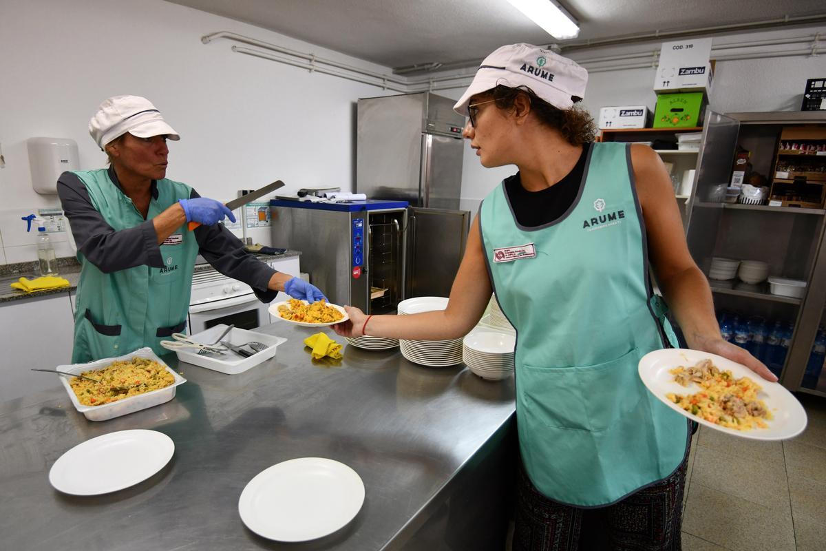 Un comedor escolar de Pontevedra: personal sirviendo platos a las mesas.
