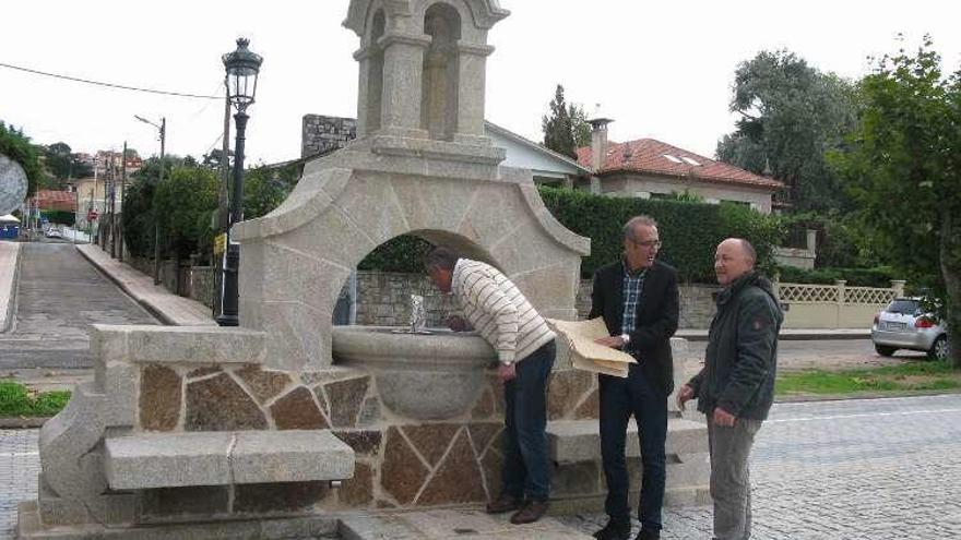 El alcalde y el edil Alfonso Parada, con un responsable de la obra, junto a la fuente rehabilitada y conectada al suministro público.