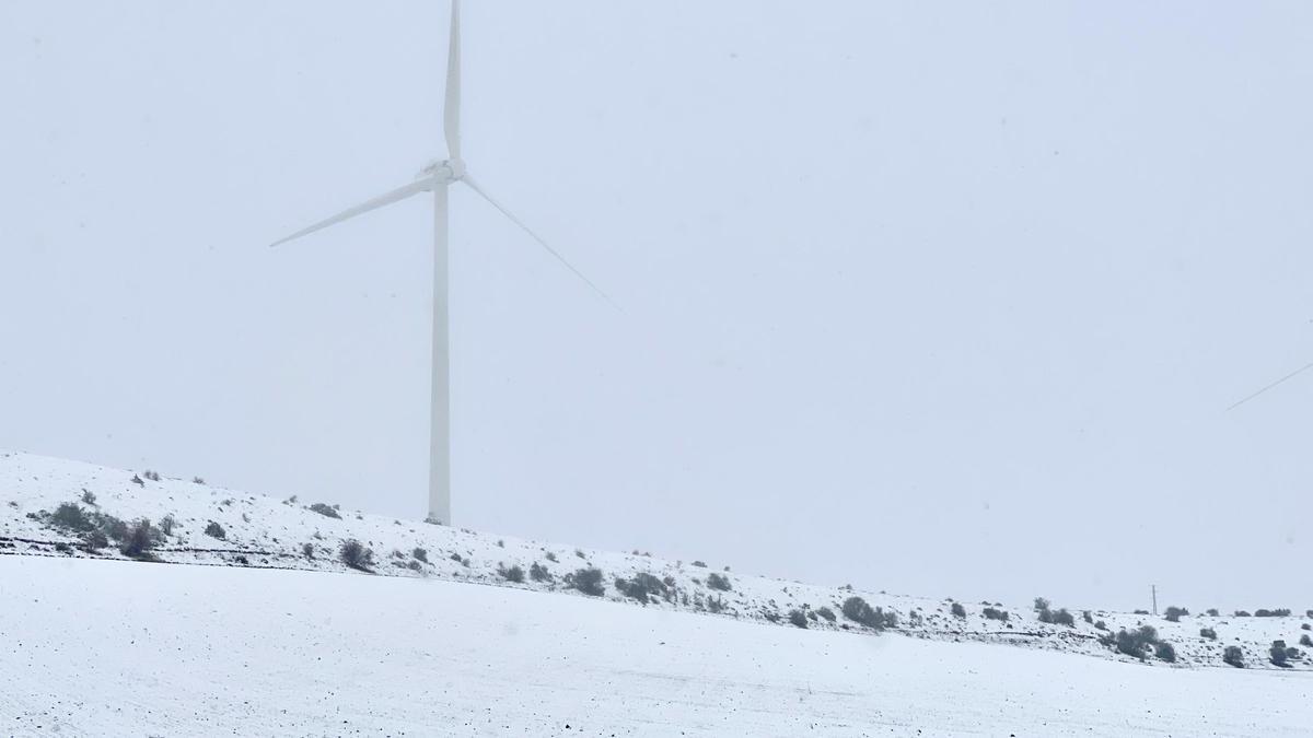 Un molino eólico en un campo cubierto de nieve.