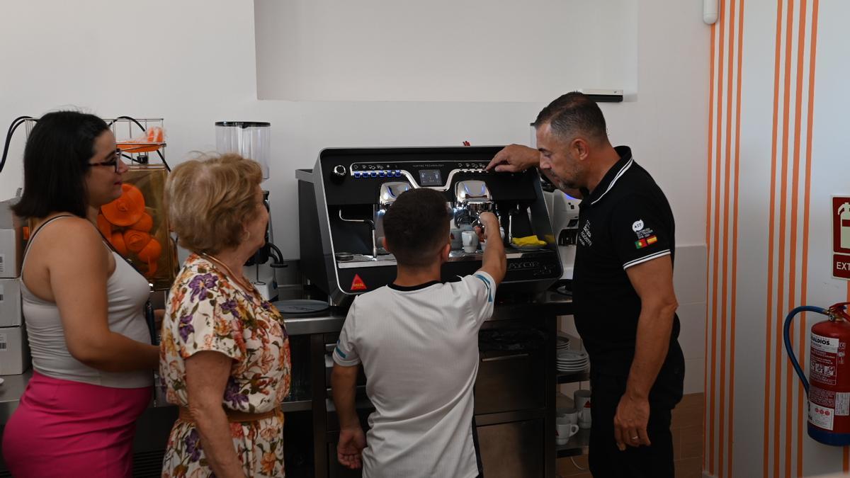 Uno de los camareros aprende a utilizar la cafetera de la nueva cafetería que en breve abrirá el Economato Social en Badajoz.