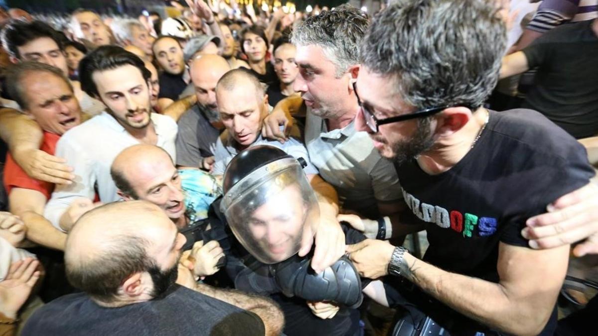 Manifestantes rodean a un policía antidisturbios.