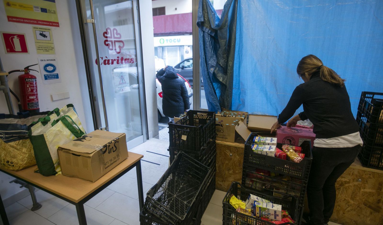 A la derercha, una voluntaria del banco de alimentos colocando paquetes.