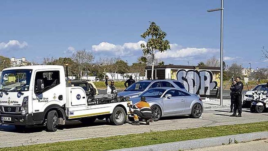 El supuesto ´vigilante´ levanta el brazo mientras el operario de la grúa se dispone a retirar su coche.