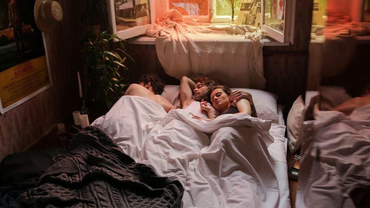 Tres personas comparten cama.