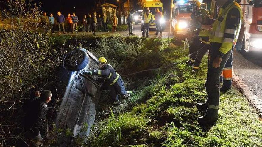 Los bomberos atan correas al coche para sujetarlo. // G. Santos