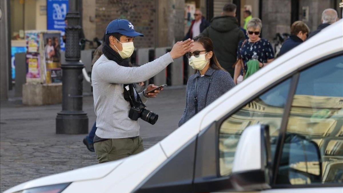 Una pareja pasea por Madrid protegida con mascarillas, por el riesgo de coronavirus