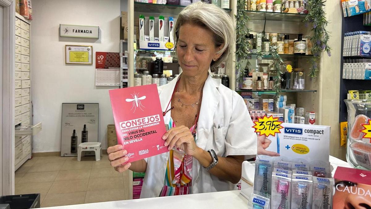 Rosario, farmacéutica sevillana, junto al folleto informativo de prevención frente al Virus del Nilo Occidental.