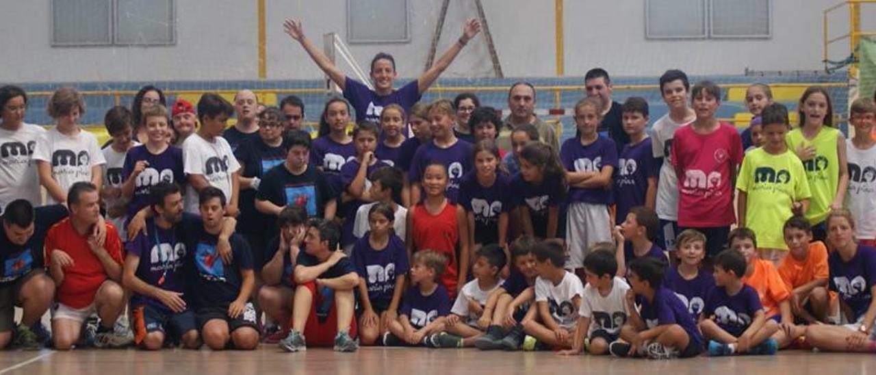 Los participantes en el Campus de Baloncesto Maria Pina posan juntos tras la finalización de una actividad. Pina detrás, con los brazos en alto.