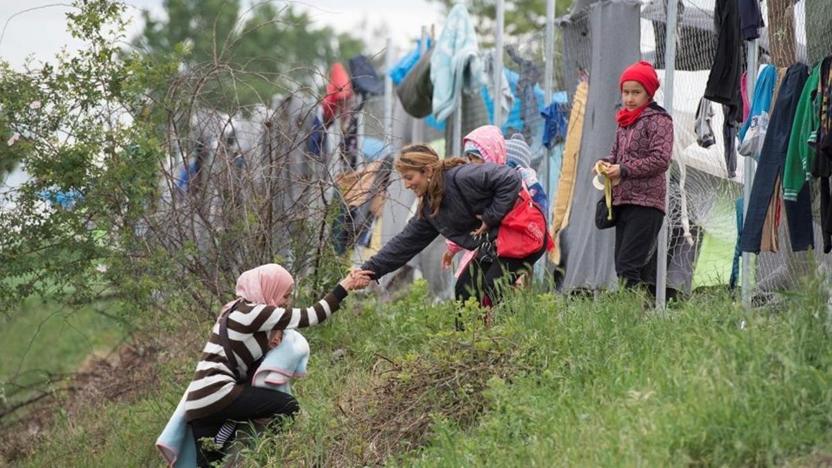 Una refugiada con su bebé en brazos, ayudada por otra a subir una colina en un campo cerca de Idomeni (Grecia), este miércoles.